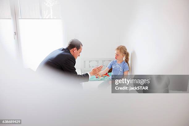 view through window of father playing hand clapping game - ohrfeige stock-fotos und bilder