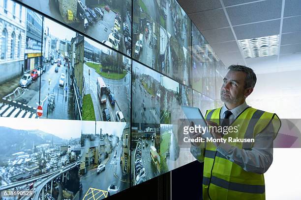 security guard using digital tablet in security control room with video wall - person with in front of screen stockfoto's en -beelden