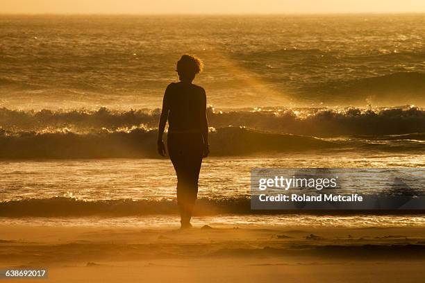 a young woman contemplates the sea, at sunset, long beach, noordhoek, cape town, western cape, south africa. - noordhoek stock-fotos und bilder