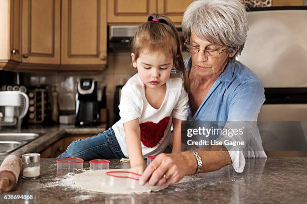 little girl making cookies with grandma - lise gagne stock pictures, royalty-free photos & images