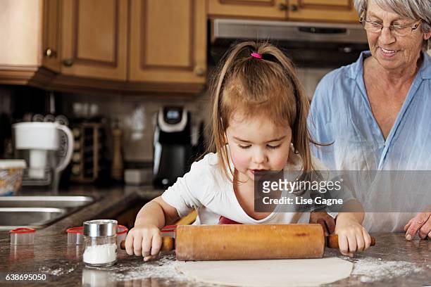 kleines mädchen macht kekse mit oma - lise gagne stock-fotos und bilder