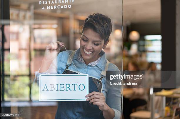 business owner holding an open sign in spanish - retail store opening stock pictures, royalty-free photos & images