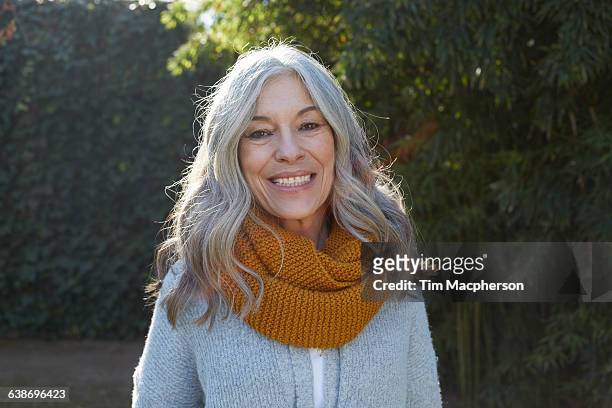 portrait of woman with long gray hair looking at camera smiling - graues haar stock-fotos und bilder