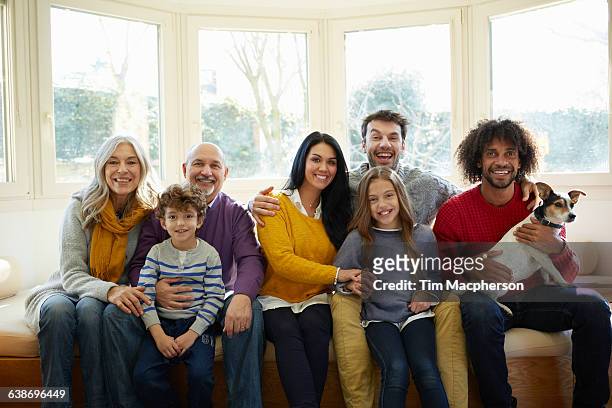 multi generation family and dog on window seat looking at camera smiling - multi generational family with pet stock pictures, royalty-free photos & images