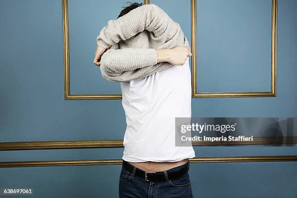 mid adult man taking off jumper - uitkleden stockfoto's en -beelden