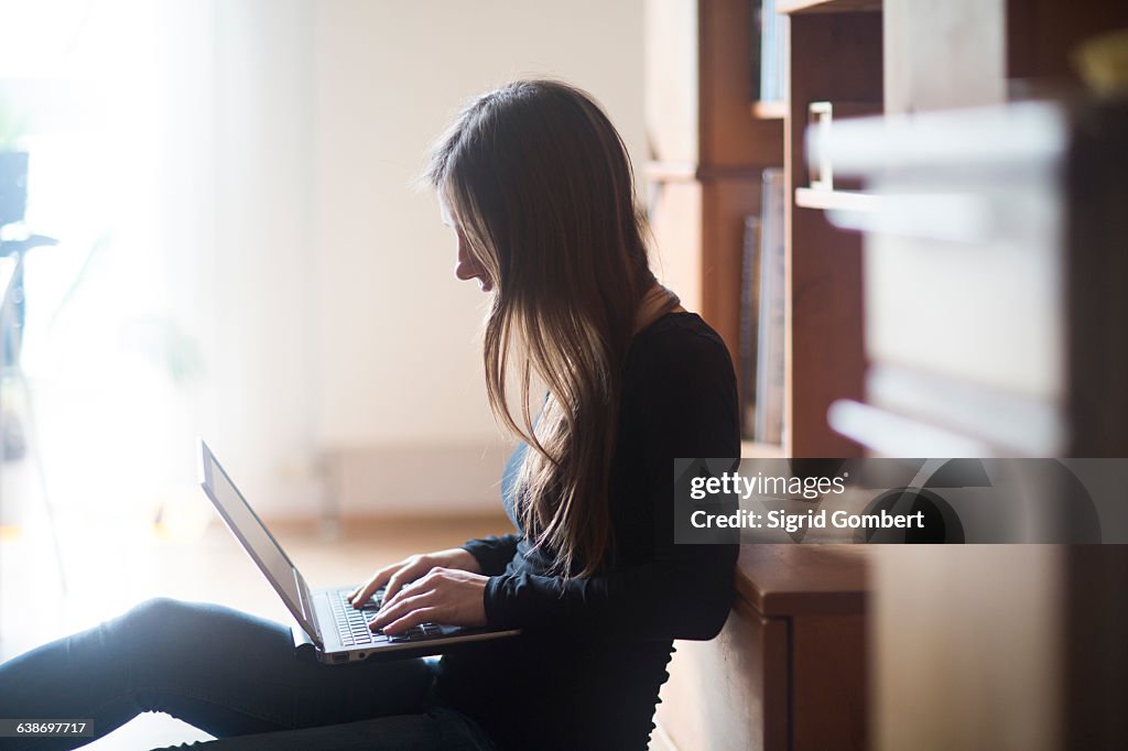 Young woman at home, using laptop