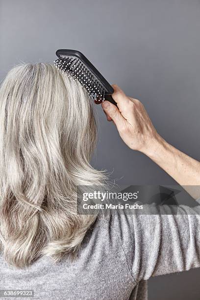 rear view of woman brushing long gray hair - long hair back stock pictures, royalty-free photos & images