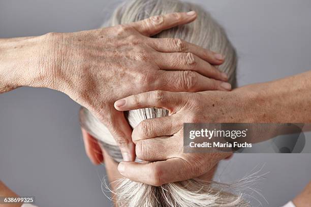 rear view of woman pulling back gray hair into ponytail - back of womens heads stock-fotos und bilder