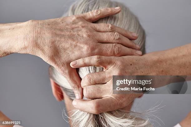 rear view of woman pulling back gray hair into ponytail - haar naar achteren stockfoto's en -beelden
