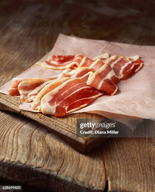 rashers of raw streaky bacon on baking paper - raw bacon stock pictures, royalty-free photos & images