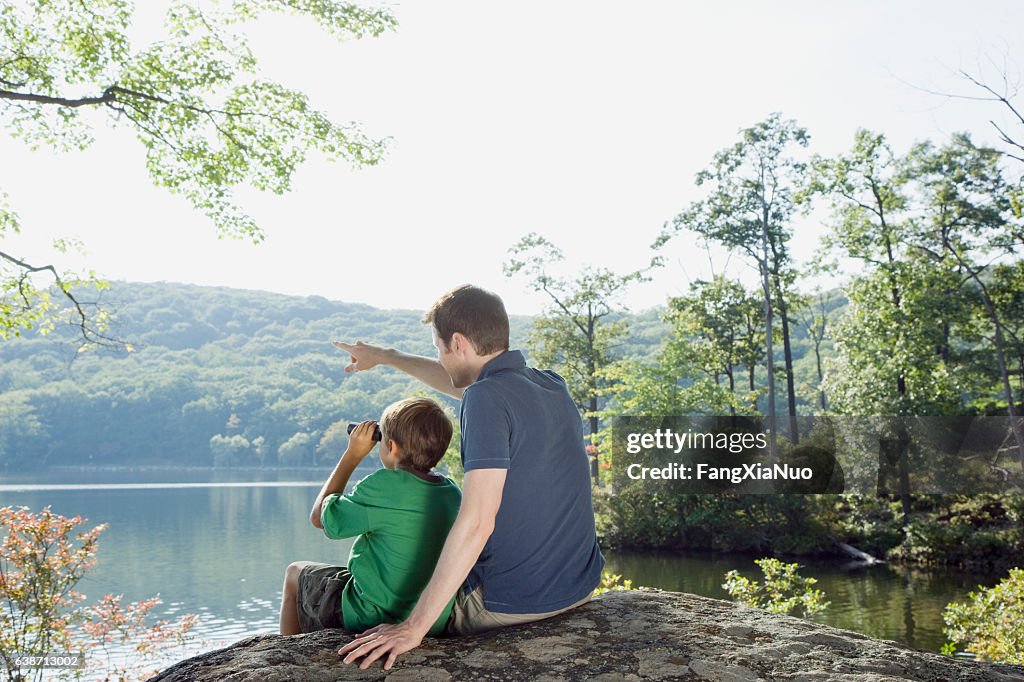 Vater und Sohn mit Fernglas mit Blick auf die Natur