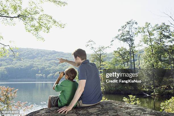 vater und sohn mit fernglas mit blick auf die natur - the god father stock-fotos und bilder