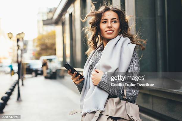 frau sms im freien - looking in bag stock-fotos und bilder