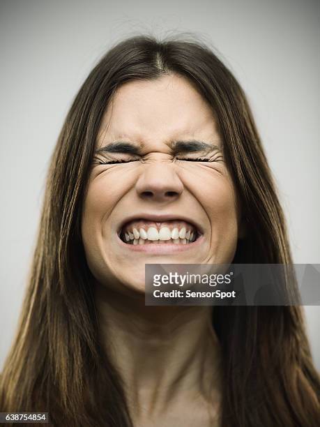 angry young woman clenching teeth - grimassen stockfoto's en -beelden