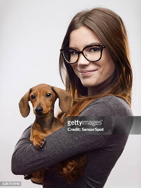 porträt einer selbstbewussten frau, die dackel trägt - woman holding dog studio stock-fotos und bilder