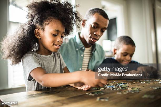 father and children doing puzzle - 4 puzzle pieces stock pictures, royalty-free photos & images