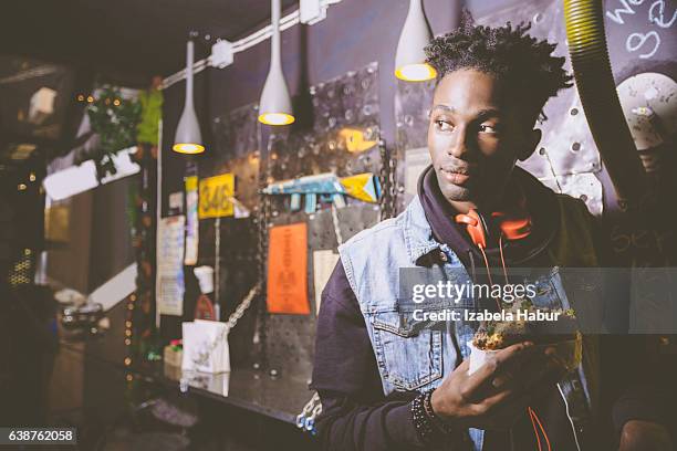 afro american young guy eating burger in pub - izabela habur stock pictures, royalty-free photos & images