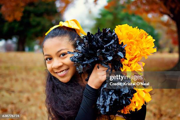 cheerleader with black and gold pom-poms - teen cheerleader stock-fotos und bilder