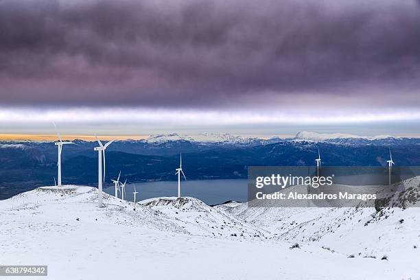 wind farm in snow at colorful sunset - alexandros maragos stock pictures, royalty-free photos & images