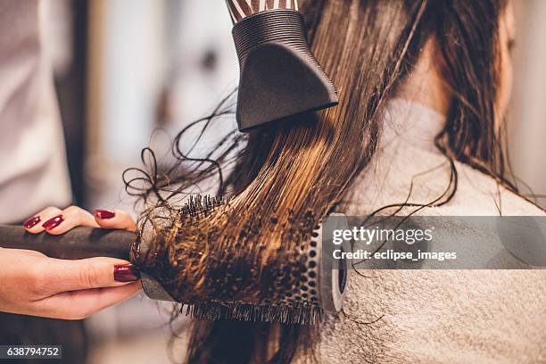 woman drying hair with a hair dryer and brush... - hand holding hair dryer stock pictures, royalty-free photos & images