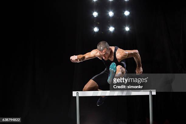 athlet springt über hürde - hurdling track event stock-fotos und bilder
