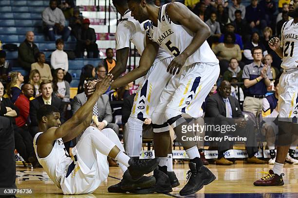 Amar Stukes is helped up by Tony Washington of the La Salle Explorers after being fouled by the George Washington Colonials during the second half at...