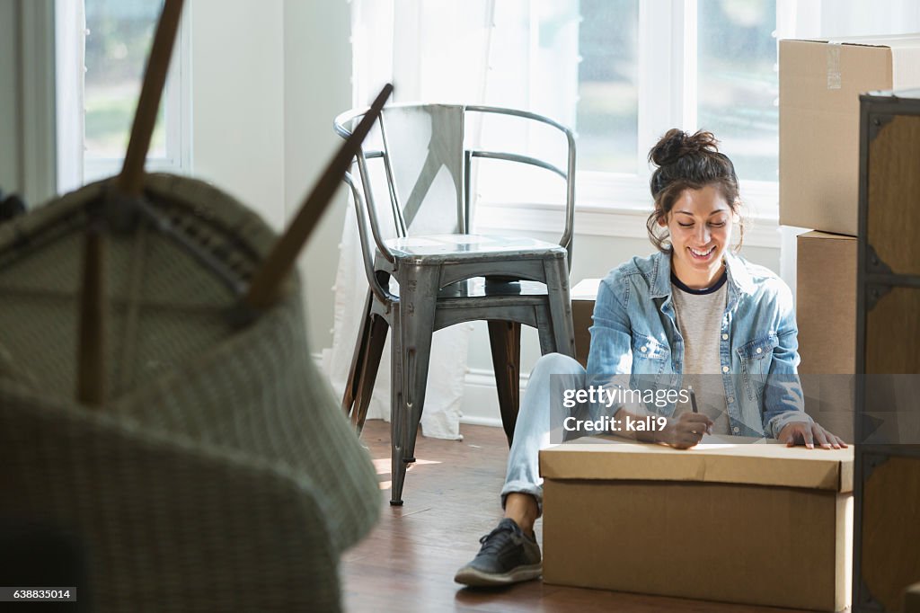 Young mixed race woman moving, writing checklist