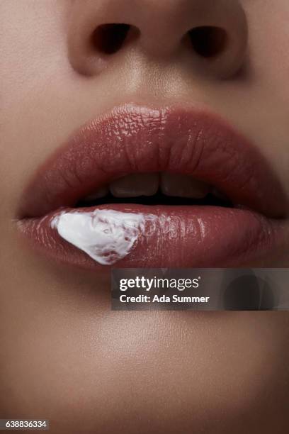 close up of female lips with cosmetic cream smear on them - cream mouth stock-fotos und bilder