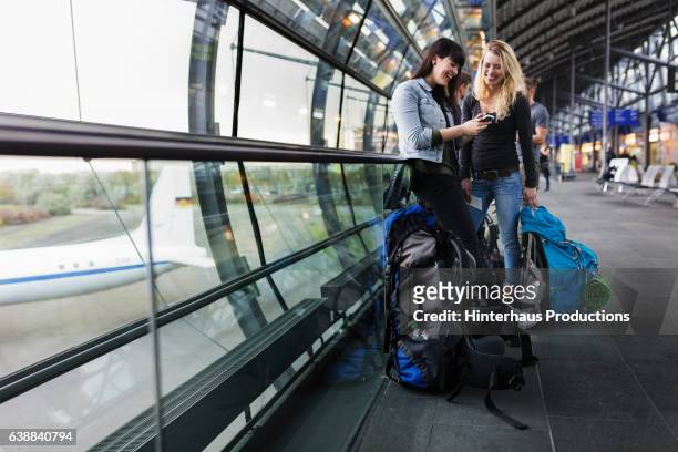 female backpackers at airport - airport smartphone stock-fotos und bilder