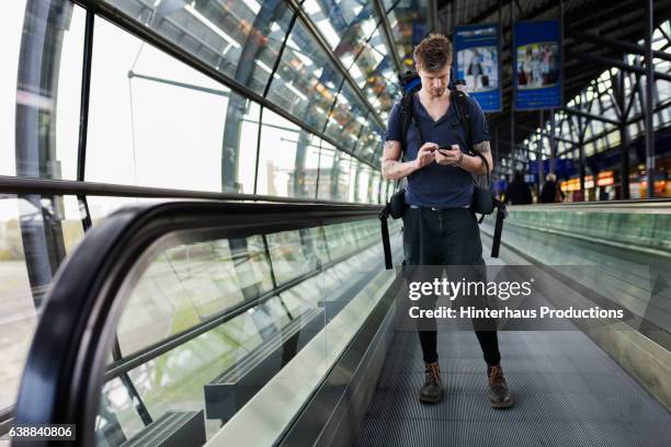 backpacker using mobile phone at airport - travolator stock-fotos und bilder