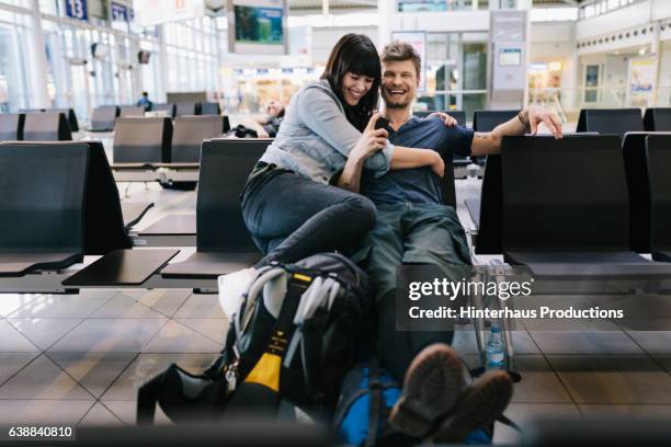 couple in airport departure lounge  - mochila bolsa fotografías e imágenes de stock