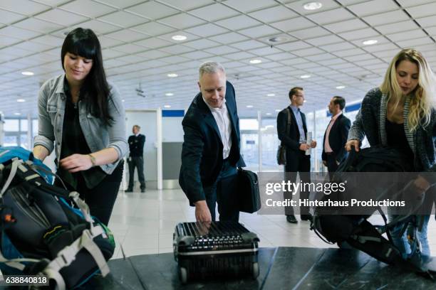 backpacker and businessman at luggage carousel - baggage claim imagens e fotografias de stock