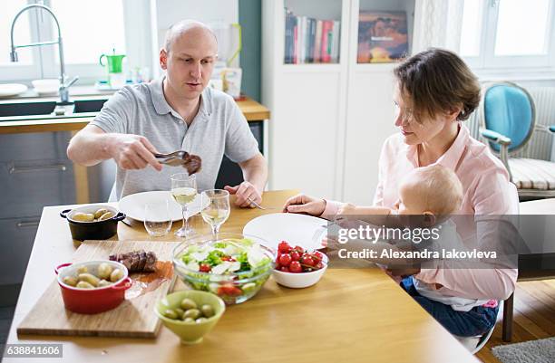 happy family eating lunch together at home - iakovleva stock pictures, royalty-free photos & images