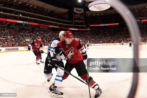 Michael Stone of the Arizona Coyotes goes after a puck in the corner while being defended by Shawn Matthias of the Winnipeg Jets at Gila River Arena...