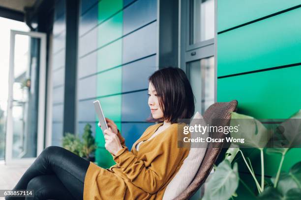 young lady reading news on tablet - asian woman reading stock-fotos und bilder