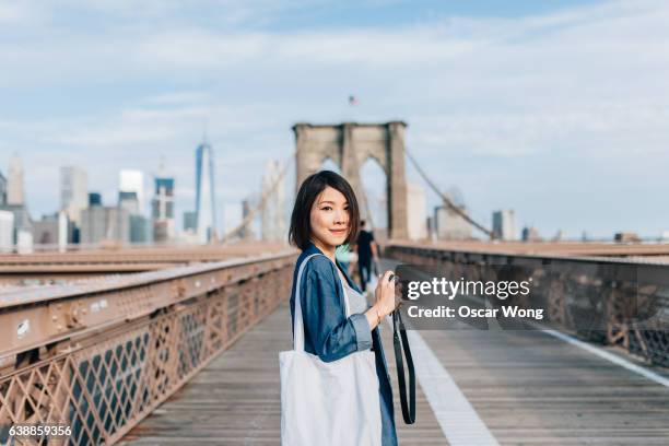 female tourist taking picture on brooklyn bridge - new york tourist stock-fotos und bilder