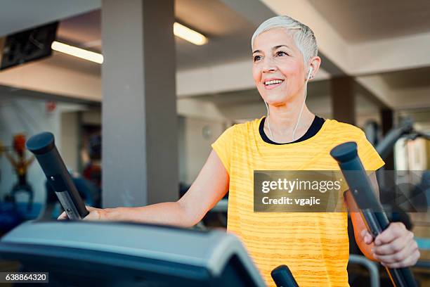 mature woman exercising in gym. - cross trainer stock pictures, royalty-free photos & images
