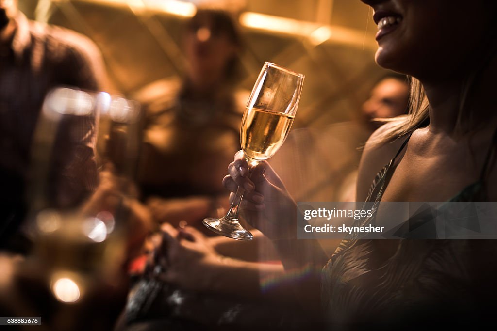 Close up of woman holding glass of Champagne in nightclub.
