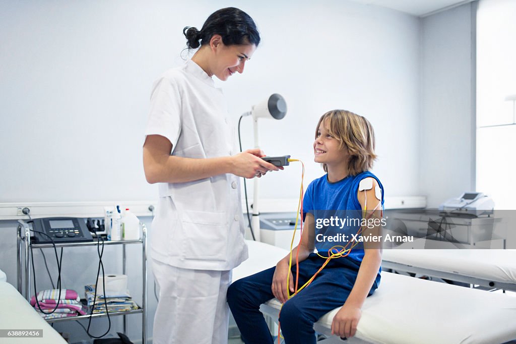 Nurse using muscle stimulator machine on boy