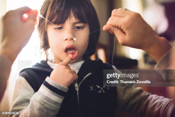 5 year old boy looking his milk tooth on a string