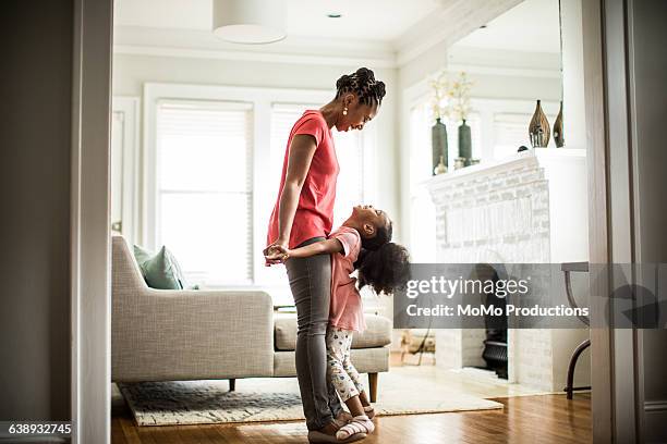 girl standing on mothers feet - images of black families stockfoto's en -beelden