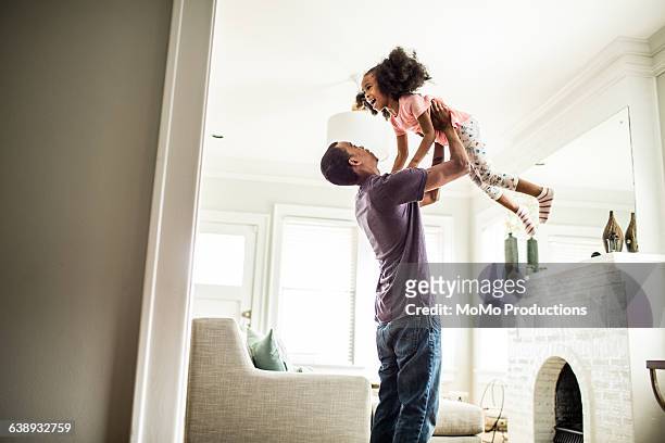 father lifting daughter in the air - sollevare foto e immagini stock