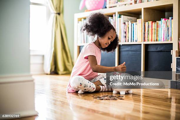 girl putting money in piggybank - home savings stock pictures, royalty-free photos & images