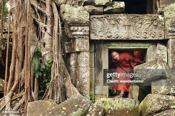 monk exploring old ruins - traditionally cambodian 個照片及圖片檔