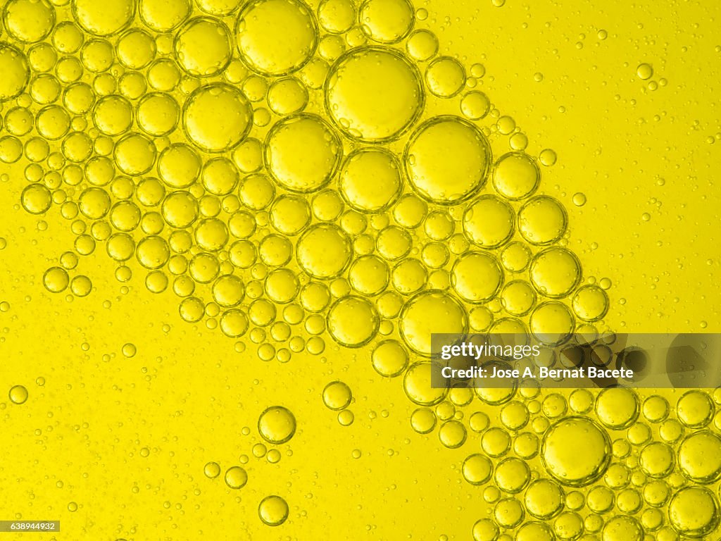 Full frame of the textures formed by the bubbles and drops,  on a smooth yellow background