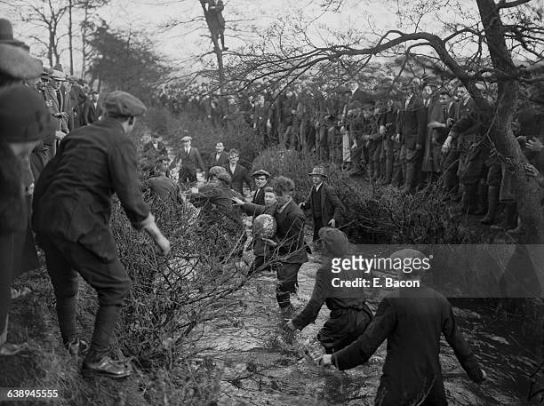 Players tussling for the ball in the brook during the Royal Shrovetide Football Match, Ashbourne, Derbyshire, 7th February 1926. The game is played...