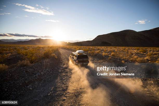 driving a dusty road - nevada stock pictures, royalty-free photos & images