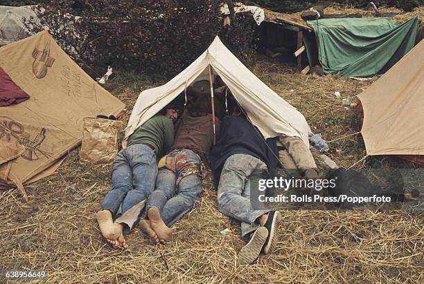 View of music fans, festival goers and campers lying both inside and outside a tent during the 1969 Isle of Wight Pop Festival on the English island...