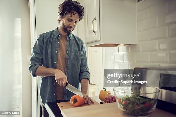 man prepares meal in kitchen - knife kitchen stock pictures, royalty-free photos & images