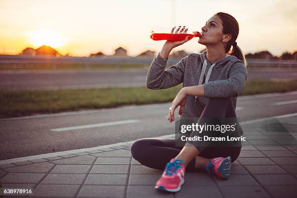 schöne frau ausruhen nach dem ausbildung ein und trinkt ein sportgetränk - energydrink stock-fotos und bilder